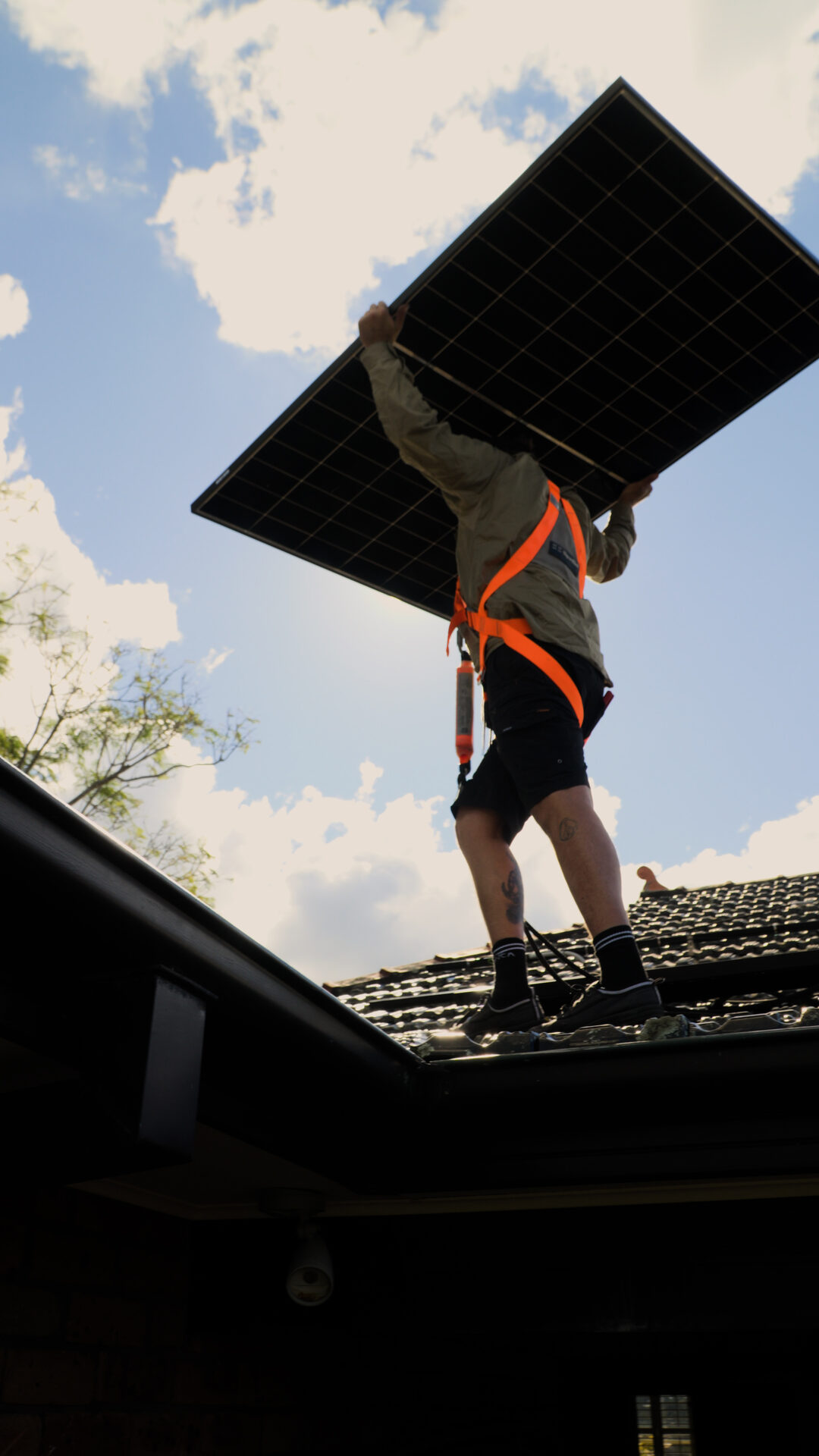 Installer carrying a solar panel on a New Lambton roof